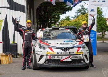 Mike Young and Amy Hudson standing on podium with Toyota TRD CH-R rally car