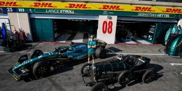 Sebastian Vettel standing between AMR22 Formula 1 car and 1922 Aston Martin TT1 Green Pea