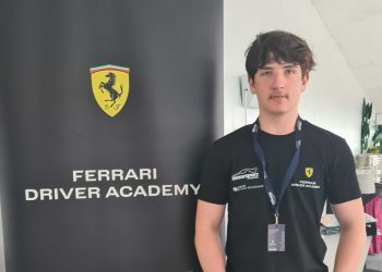 Alex Crosbie standing next to Ferrari Driver Academy banner