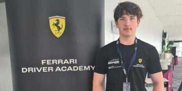 Alex Crosbie standing next to Ferrari Driver Academy banner