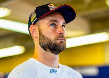 Shane van Gisbergen standing in pit garage with Red Bull can