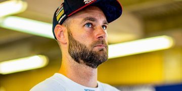 Shane van Gisbergen standing in pit garage with Red Bull can