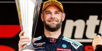 Shane van Gisbergen holding up winning trophy