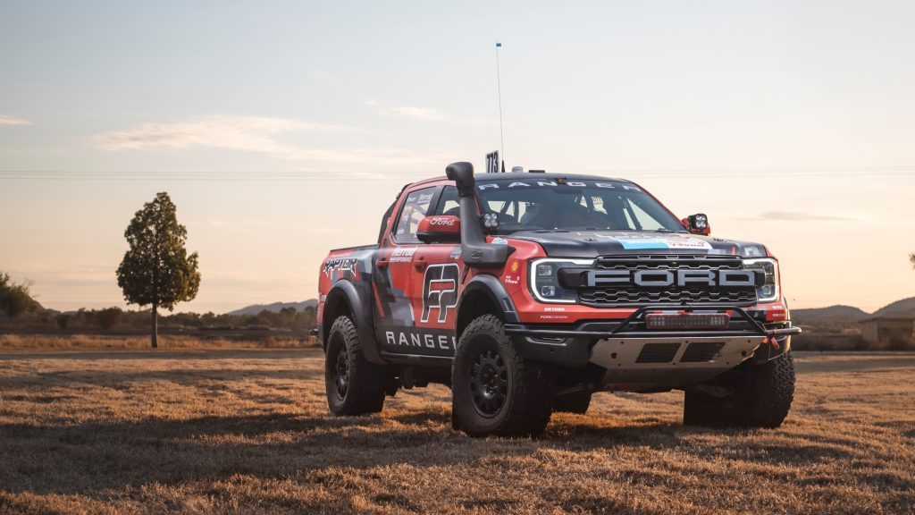 Ford Ranger Raptor race truck parked in field next to tree