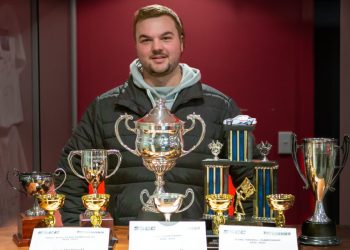 Liam MacDonald standing with trophies