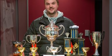 Liam MacDonald standing with trophies