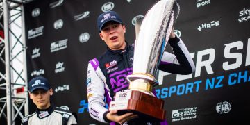 Brock Gilchrist holding up trophy on podium